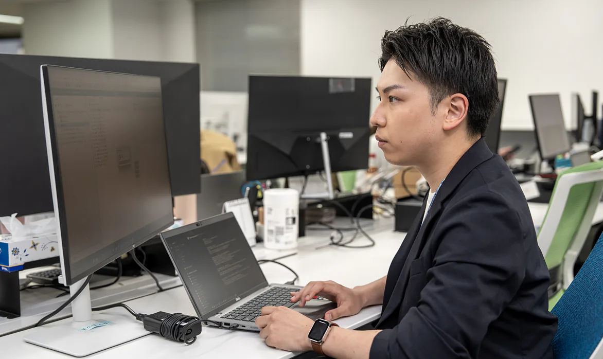 オフィスで複数のモニターを見ながら作業する男性社員