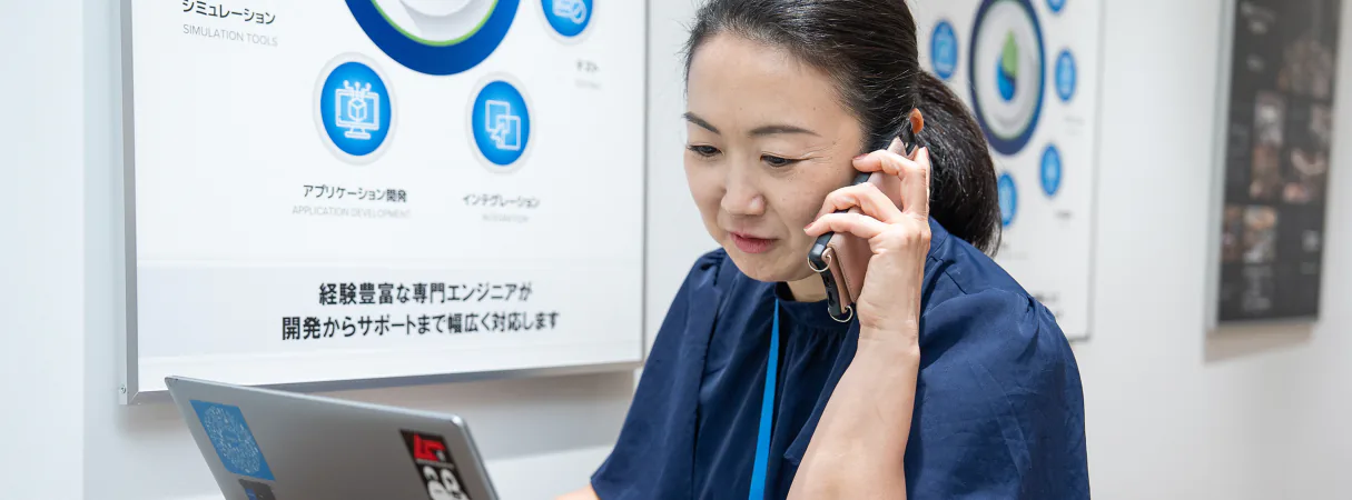 社内で電話対応をしながらパソコンを操作する女性社員